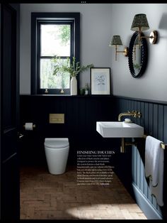 a white toilet sitting next to a bathroom sink under a window in a black and white bathroom