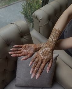 a woman with henna on her arm holding onto a pillow in front of a couch