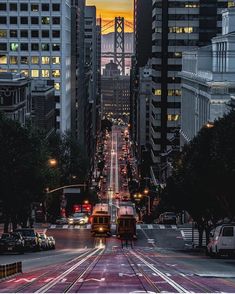 a city street filled with lots of traffic and tall buildings at night, in the background is a golden gate bridge