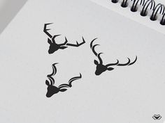 two deer head stickers on a spiral bound notepad, next to a pen