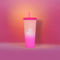 a pink and white cup sitting on top of a table next to a neon colored wall