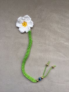 a crocheted flower is attached to a green string with beads and bead