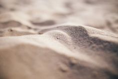 the sand is white and brown with little patches of black dots on it's surface