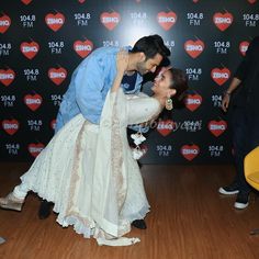 a man and woman dancing on a wooden floor in front of a red heart backdrop