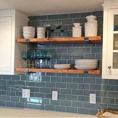 a kitchen with white cabinets and blue tile backsplash, open shelving above the sink