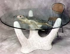 a turtle sitting on top of a glass table next to a chair and armrests