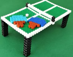 a small table made out of legos on a green surface with black legs and feet