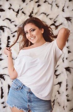 a woman posing for a photo with her hair in the air and wearing a white shirt