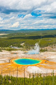 an aerial view of a blue and yellow crater in the middle of a forest area