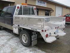 a truck parked in front of a building with snow on the ground and two cars behind it