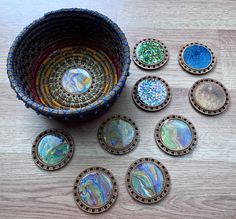 a bowl filled with lots of different types of glass coasters on top of a wooden table