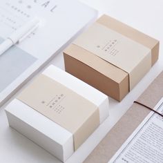 two boxes sitting next to each other on top of a white table with papers and scissors