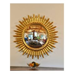 a sun shaped mirror on the wall above a bowl with fruit in front of it