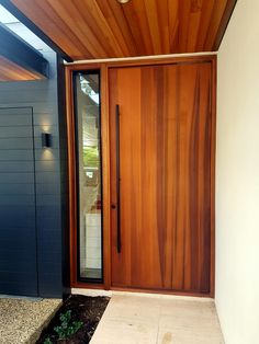 a wooden door is open on the side of a house with plants in the ground