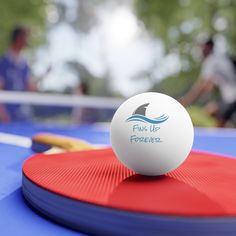 a ping pong ball sitting on top of a blue table with paddles next to it