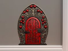 an ornately decorated red door is on display in a room with gray walls and white trimmings