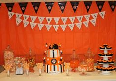 an orange and black dessert table with lots of candy