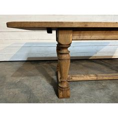 an old wooden table sitting in front of a white wall