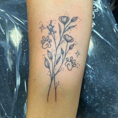 a black and white photo of a flower tattoo on the left arm, with stars in the background