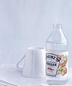 a bottle of vinegar sitting on top of a white towel next to a glass cup