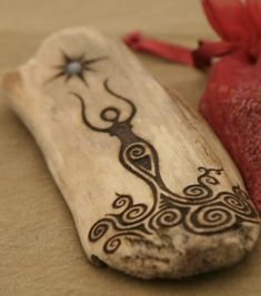 a piece of wood with an intricate design on it and a red ribbon tied around it