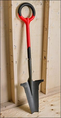 a red and black garden tool hanging on a wall