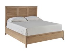 a bed with white sheets and wooden headboard