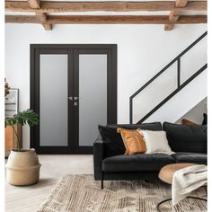 a living room filled with furniture and a stair case in front of a black door