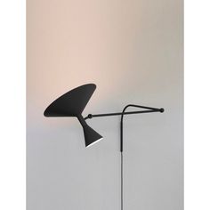 a black lamp on a white wall next to a floor lamp with a long arm