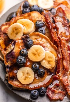 pancakes with bacon, blueberries and bananas on a plate