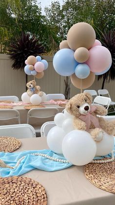 a teddy bear sitting on top of a cloud filled with balloons