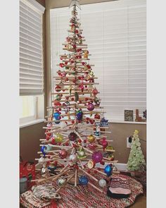 a christmas tree made out of wooden sticks with ornaments on top and around the base