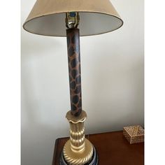 a lamp with a giraffe print shade on the base and a wooden table