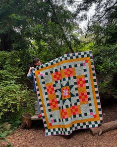 a person standing next to a quilt in the woods