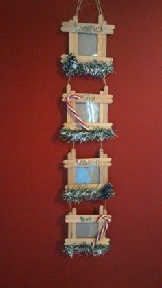 three wooden frames with candy canes and christmas decorations hanging on a red painted wall