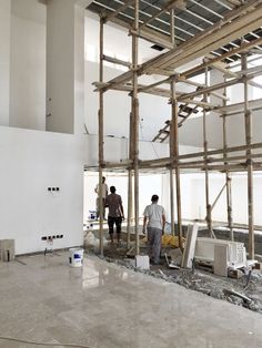 two men standing in the middle of a building under construction