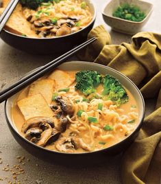 two bowls filled with noodles, broccoli and mushrooms