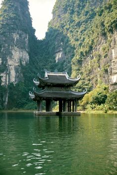 a building sitting on top of a lake surrounded by mountains