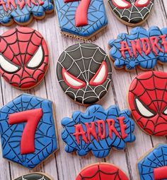 decorated cookies with spiderman faces and the number seven are on a white tablecloth