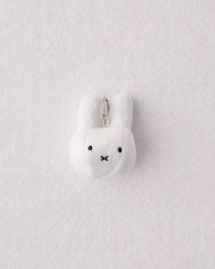 a white stuffed animal keychain hanging on a wall