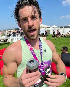 a man holding a water bottle in his hand and wearing a medal around his neck