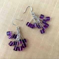 a pair of earrings with purple beads hanging from them