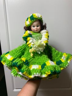 the doll is wearing a green and yellow dress with flowers on it's skirt