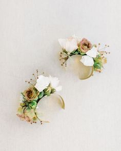 two white vases filled with flowers on top of a table