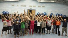 a group of people holding up their hands in the air with blue balls on them