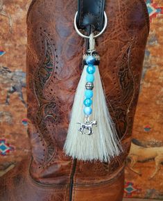 a cowboy boot with a tassel hanging from it's side and a horse charm