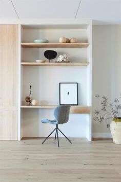 a chair and some shelves with vases on them in a room that has wood flooring