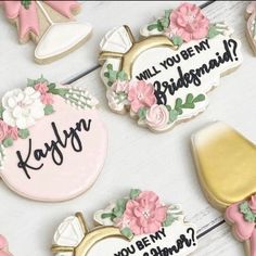 decorated cookies that say will you be my bridesmaid? and have pink flowers on them