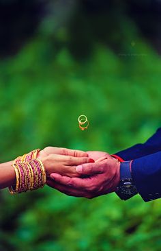 the bride and groom are holding each other's hands with their wedding rings flying in the air