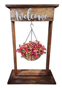 a welcome sign hanging from a wooden frame with flowers in the pot and letters above it